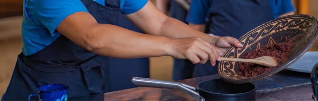 Person cooking with wooden spoon and decorative bowl in kitchen