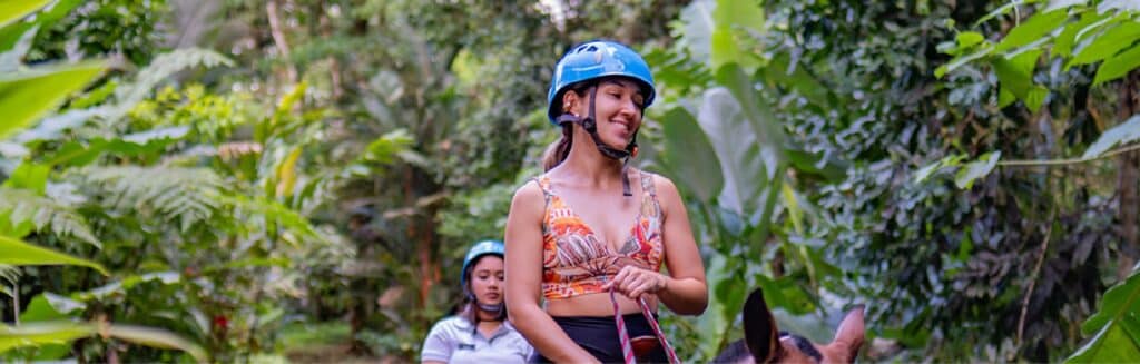 Woman horseback riding in lush tropical forest adventure